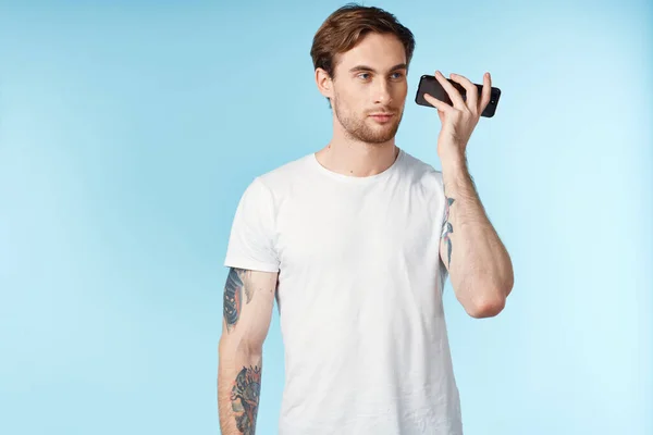 Чоловік з татуюваннями на руках біла футболка обрізаний вид синій фон — стокове фото