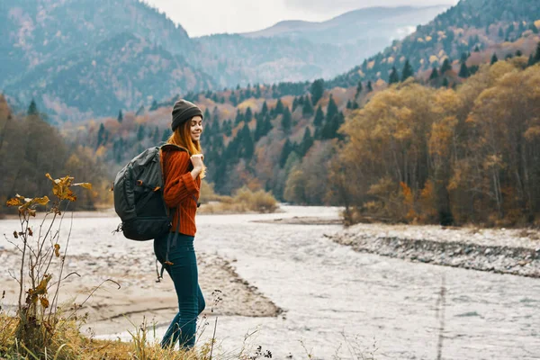 Donna in jeans e una giacca con uno zaino vicino al fiume in montagna paesaggio natura — Foto Stock