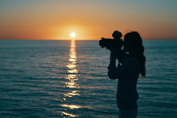 Fotograf mit Kamera bei Sonnenuntergang am Meer — Stockfoto