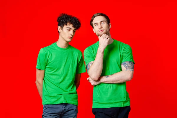 Yeşil tişörtlü iki neşeli arkadaş birbirlerinin yanında duruyor. Duygularını dışa vurmuyorlar. — Stok fotoğraf