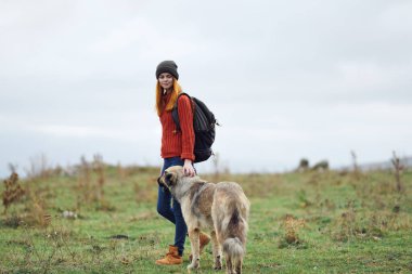 Sırt çantalı bir kadın yürüyüşçü köpeği dağlarda gezdirir arkadaşlık seyahati
