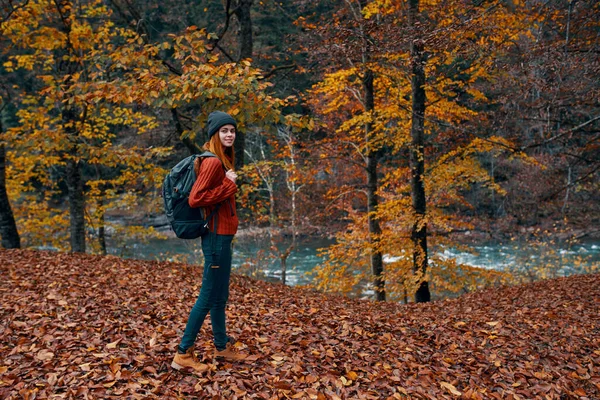 Een reiziger met een rugzak wandelingen in het park in de natuur in de buurt van de rivier in de herfst — Stockfoto