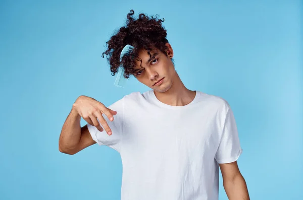 Homem bonito com cabelo encaracolado segurando pente na mão e fundo azul corte vista — Fotografia de Stock