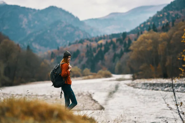 Femme en vacances avec un sac à dos sur la rive de la rivière dans les montagnes — Photo