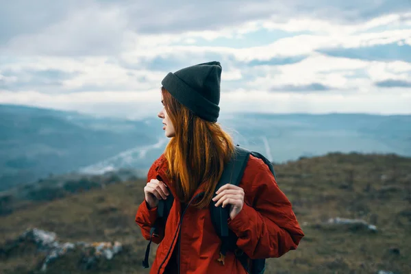 Mulher viaja nas montanhas paisagem mochila casaco vermelho e chapéu modelo — Fotografia de Stock