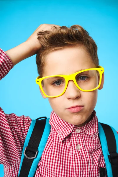 Skolpojke med ryggsäck bär glasögon närbild blå bakgrund utbildning — Stockfoto