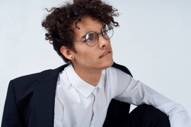 Ceketli ve gözlüklü kıvırcık saçlı bir adamın portresi. 