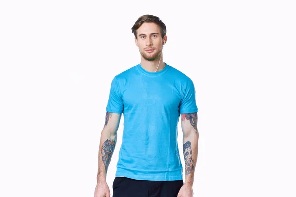 Atleta com halteres em um fundo leve e azul t-shirt calças tatuagem — Fotografia de Stock