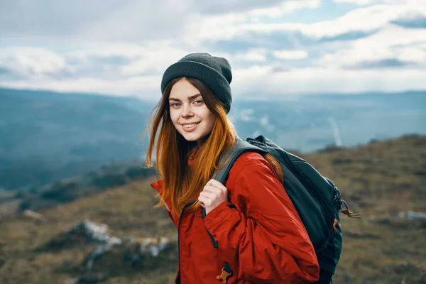 Портрет путешественника в красной куртке и шляпе и с рюкзаком на открытом воздухе в горах — стоковое фото