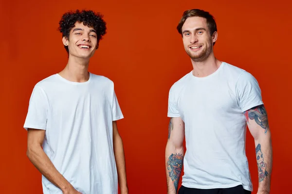 Due uomini in t-shirt bianche su sfondo rosso amicizia — Foto Stock