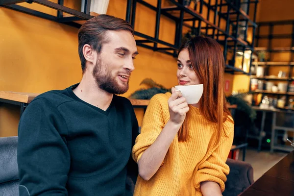 Egy nő szerelmes egy csésze kávéba és egy boldog férfi egy asztalnál egy kávézó belsejében barátok kommunikáció — Stock Fotó