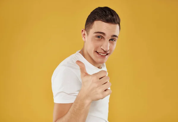 Homem bonito em branco t-shirt gesticulando com as mãos amarelo fundo — Fotografia de Stock