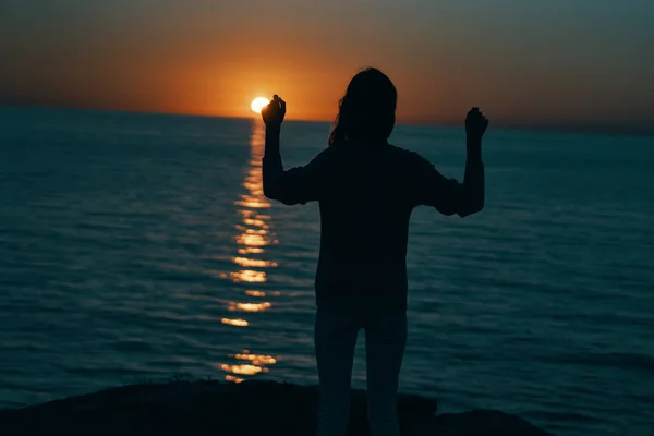 female silhouette on the beach near the sea at sunset. High quality photo