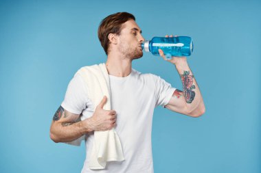 Spor adamı omzundaki spor havlusundan su içiyor.