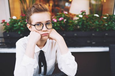 Kısa saçlı üzgün kadın kafeterya masasında bir sandalyede oturuyor. Duygular kitabı.