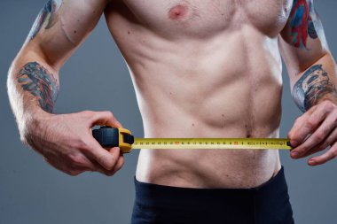 Ateşli kol kasları ve santimetre bant vücut geliştirici formda seksi bir sporcu.