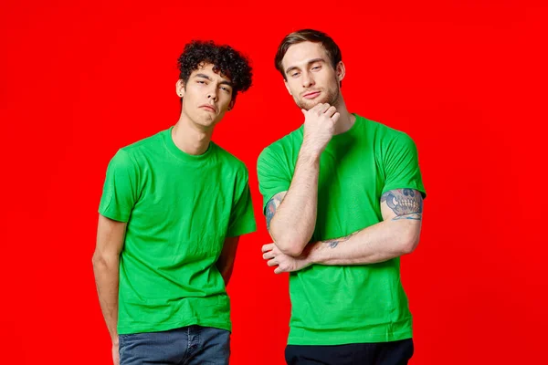 Due amici allegri in t-shirt verdi sono in piedi uno accanto all'altro emozioni isolato sfondo — Foto Stock