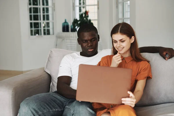 Homme et femme à la maison sur le canapé avec un ordinateur portable bavarder en ligne — Photo