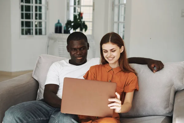 Jeune couple à la maison sur le canapé devant l'ordinateur portable — Photo