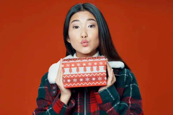 Frau asiatischen Aussehens hält ein Geschenk roten Hintergrund — Stockfoto