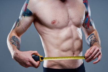 Ateşli kol kasları ve santimetre bant vücut geliştirici formda seksi bir sporcu.