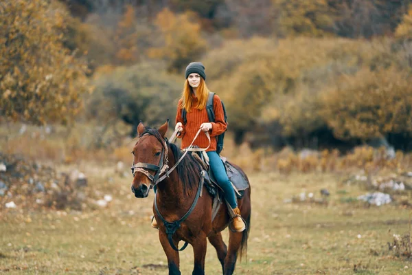 Mujer excursionista monta un caballo en un campo montañas naturaleza paisaje — Foto de Stock