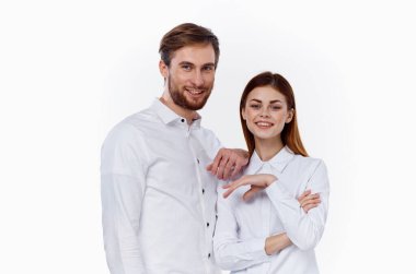 Beyaz gömlekli kadın ve erkek yan yana gülümseyerek iletişim kuruyorlar.