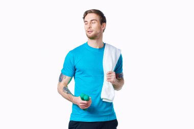 Elinde dambıllar, omuzlarında havluyla egzersiz yapan sportif bir adam.