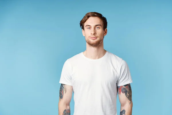 Man med tatueringar på armarna vit t-shirt beskärd vy blå bakgrund — Stockfoto