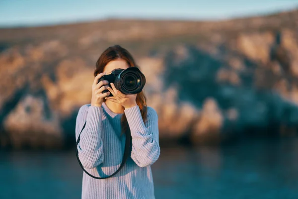 Portrait of a woman photographer with a professional camera outdoors in the mountains — Stock Photo, Image