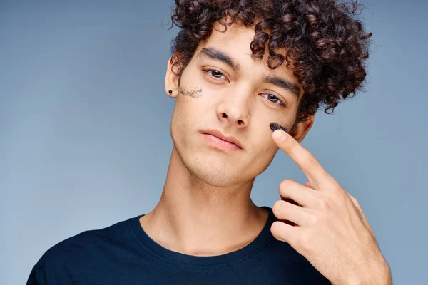 Stilig kille med lockigt hår använder en svart mask på ansiktet kosmetologi — Stockfoto
