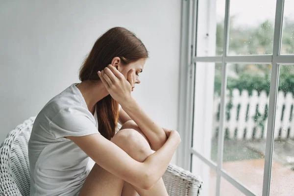 Vrouw thuis zitten in een stoel in de buurt van het raam eenzaamheid depressie — Stockfoto