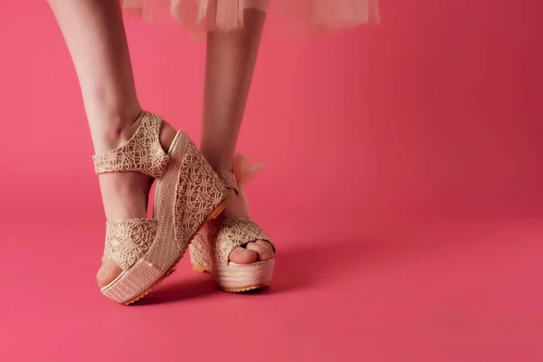 Gambe femminili in scarpe beige posa primo piano sfondo rosa — Foto Stock