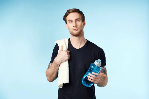 Atletico uomo bere acqua energia allenamento blu sfondo — Foto Stock