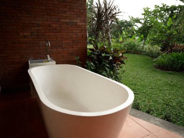 Beyaz banyo tuğla duvarın yanında ve arka planda doğa ile bütünlük var.