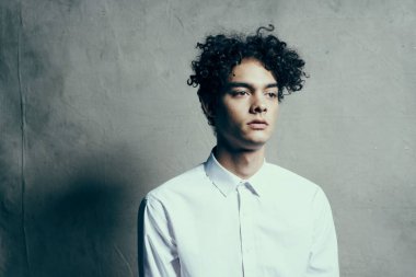 Kıvırcık saçlı beyaz gömlekli adam stüdyo yaşam tarzını yönetiyor.