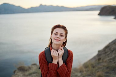 Kadın doğada, deniz kenarında, dağlarda seyahat eder. Günbatımı yaşam tarzını görür.