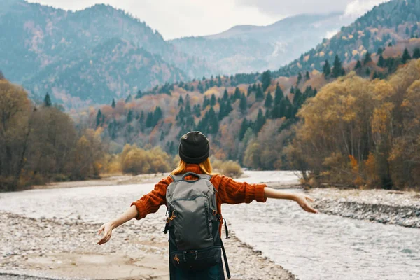 Vrouw houdt haar handen boven haar hoofd in de bergen buiten in de herfst in de buurt van de rivier reizen — Stockfoto