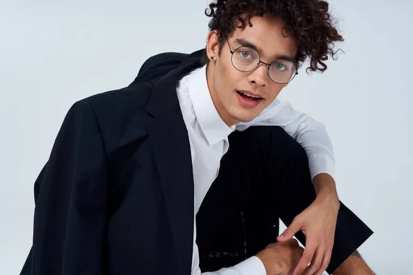 Cara bonito em uma jaqueta e camisa e óculos em um quarto brilhante foto estúdio modelo penteado cabelo encaracolado — Fotografia de Stock