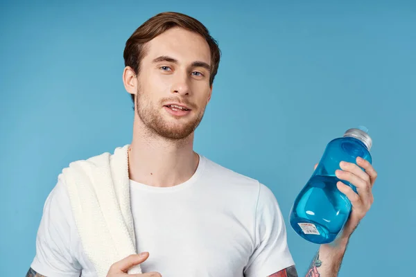 Allegro uomo sportivo in bianco t-shirt acqua bottiglia energia blu sfondo — Foto Stock