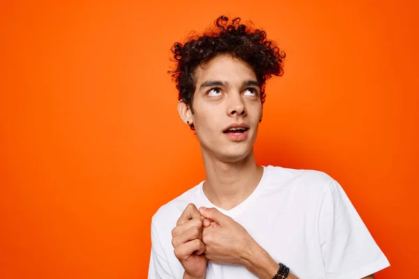 Lindo chico rizado pelo emociones mueca estudio naranja fondo — Foto de Stock