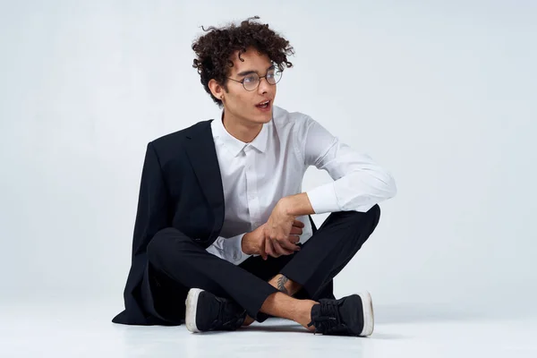 Jovem elegante com cabelo encaracolado e em um terno clássico em um fundo leve dentro de casa em pleno crescimento — Fotografia de Stock