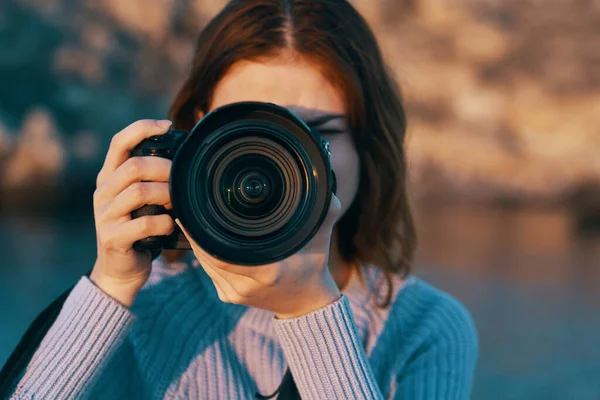 Donna dai capelli rossi con una macchina fotografica sulla natura nelle montagne vicino al fiume — Foto Stock