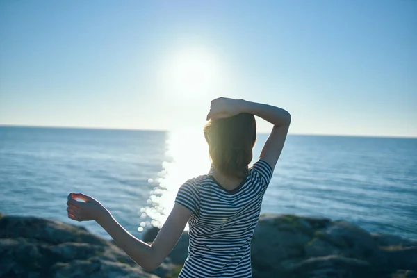 Happy traveler woman gesturing with her hands near the sea in nature and sunset in the distance — Stock Photo, Image