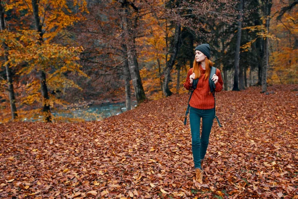 Turystyka turystyczna i młoda kobieta z plecakiem spacery w parku w przyrodzie krajobraz wysokie drzewa spadły liście rzeki — Zdjęcie stockowe