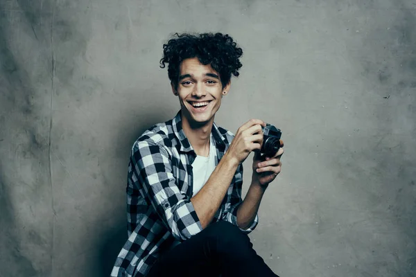 Stilig manlig modell i en skjorta och en t-shirt på en grå bakgrund lockigt hår frisyr kamera Studio — Stockfoto