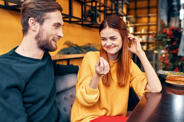 Красивый мужчина и счастливая женщина в свитере сидят за столом в кафе чата интерьер комнаты — стоковое фото