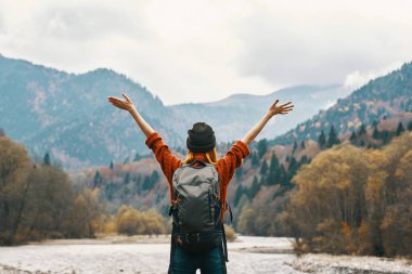 Sırt çantalı kot giyen bir kadın sonbaharda doğada gezer.