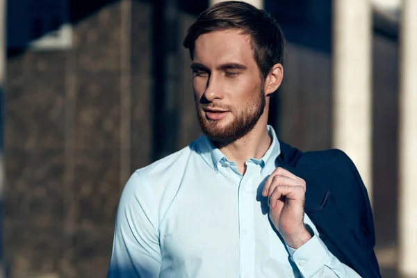 Fashionable man in blue shirt with jacket on shoulder on street near building cropped view — Stock Photo, Image