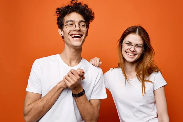 Beyaz tişörtlü ve gözlüklü genç çift eğlenceli moda turuncu arka plan — Stok fotoğraf
